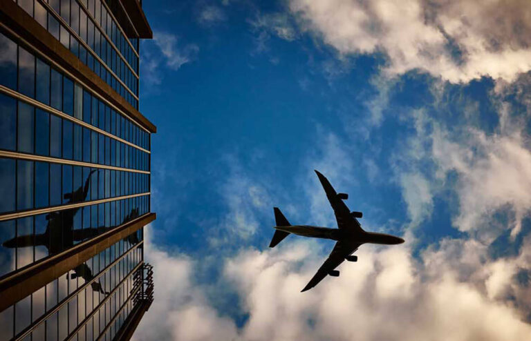 airplane flying in sky over office buildings