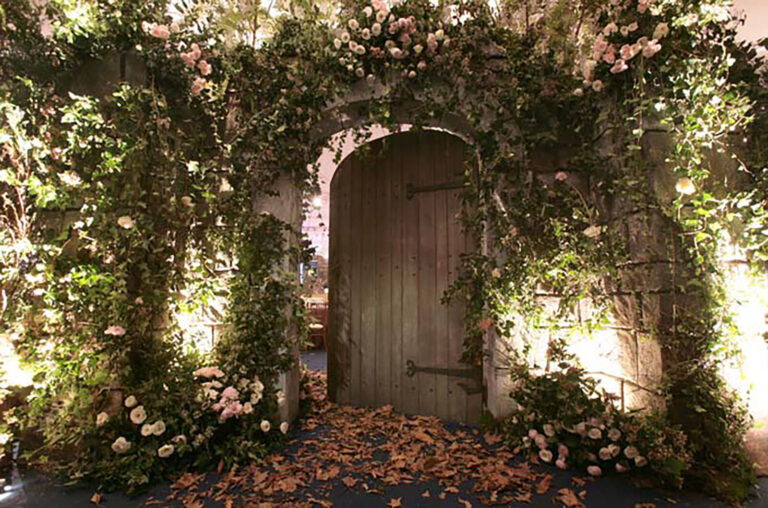 Flower covered door in a stone wall set at British Red Cross London Ball Secret Garden theme fundraising event