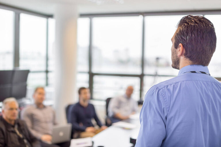 man presenting to colleagues in a meeting room