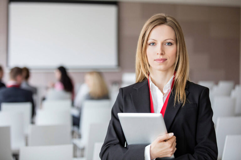 corporate event / meeting planner holding tablet with meeting room in background