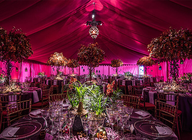 dining tables set up for a dinner event in a pink Raj tent