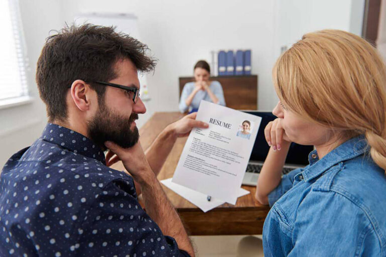 male and female employers discussing a candidates resume in front of them at a job interview