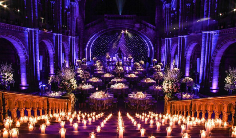 the Natural History museum bathed in purple light and candles set up for a dinner event