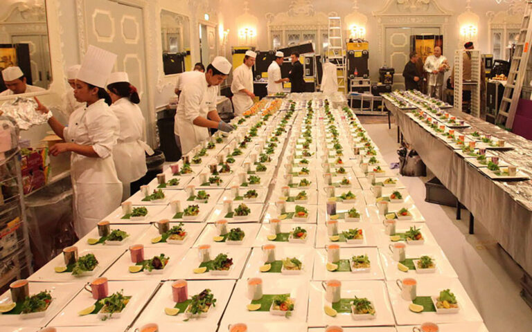 event chefs plating rows of dishes in the backstage kitchen area of the Dorchester Hotel ballroom