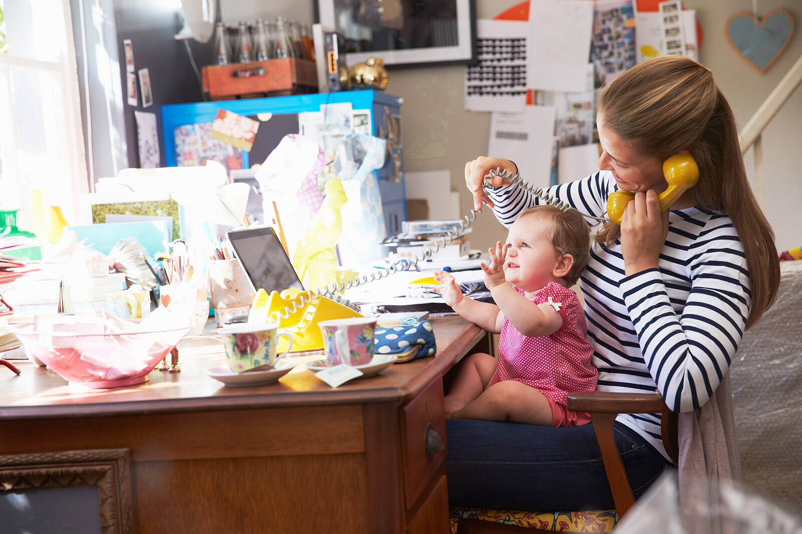 event planner working from home with child on lap while on the telephone