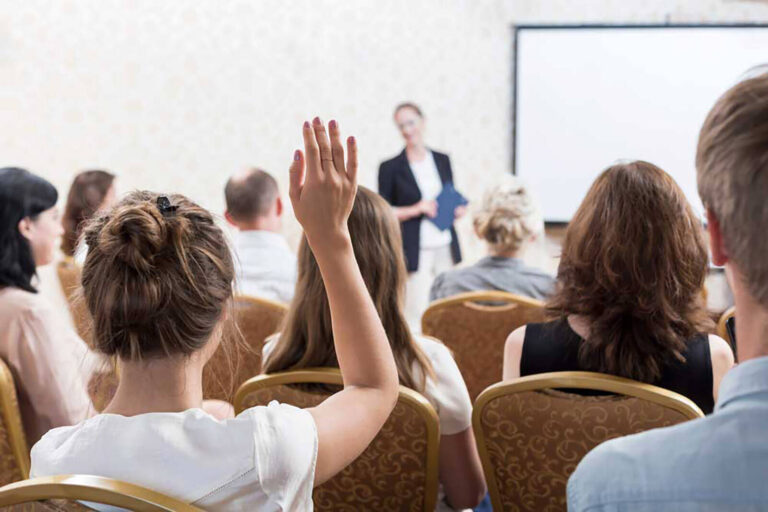 class of event planning course students with one raising hand to ask a question
