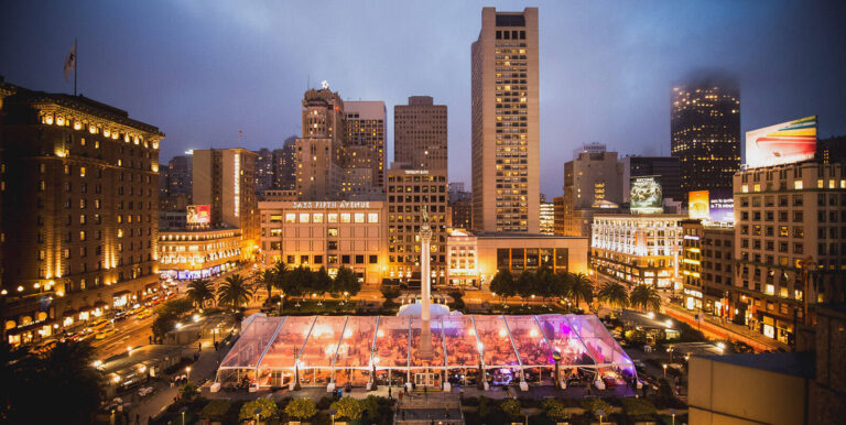 dinner in transparent tent in a city square surrounded by buildings by ACCESS Destination Services