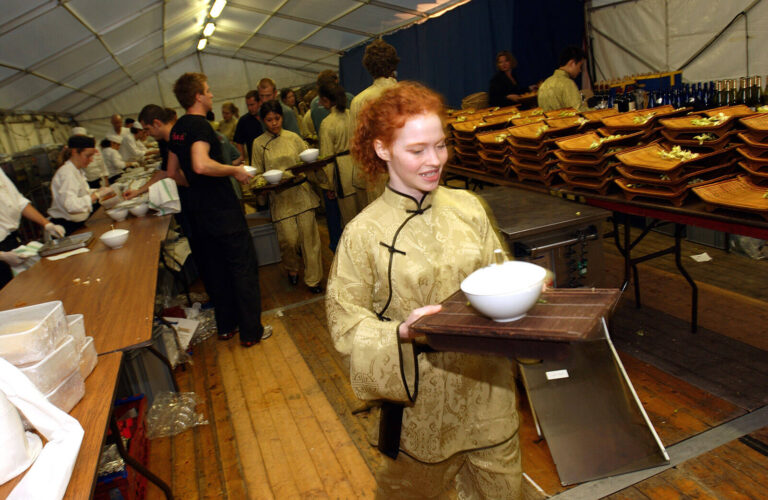 wait staff carrying plates in a special event catering kitchen