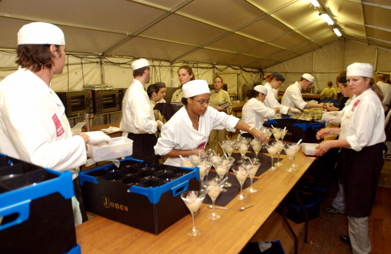 event catering staff and chefs plating dishes in a special event catering kitchen