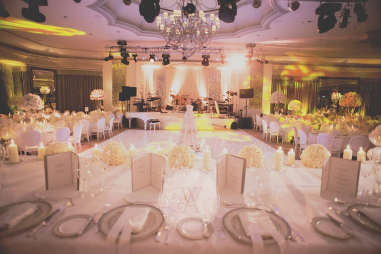 dining tables, stage, and dancefloor in the ballroom of The Dorchester Hotel set up for a wedding reception